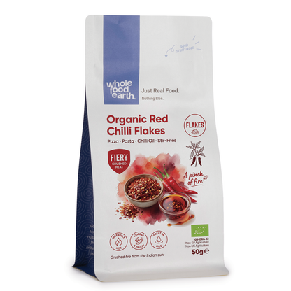 Organic red chilli flakes from Whole Food Earth, vibrant dried red chili flakes in a clear glass jar, highlighting their spicy texture.