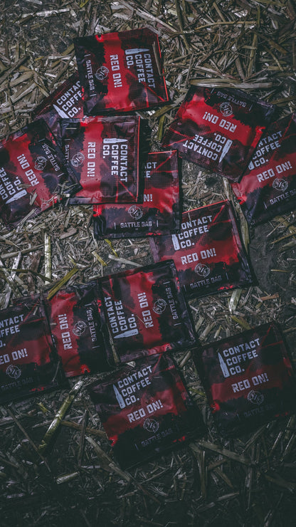 Red single-serve coffee brew bag by Contact Coffee Company Ltd., ready for brewing, with vibrant red packaging and coffee grounds inside.