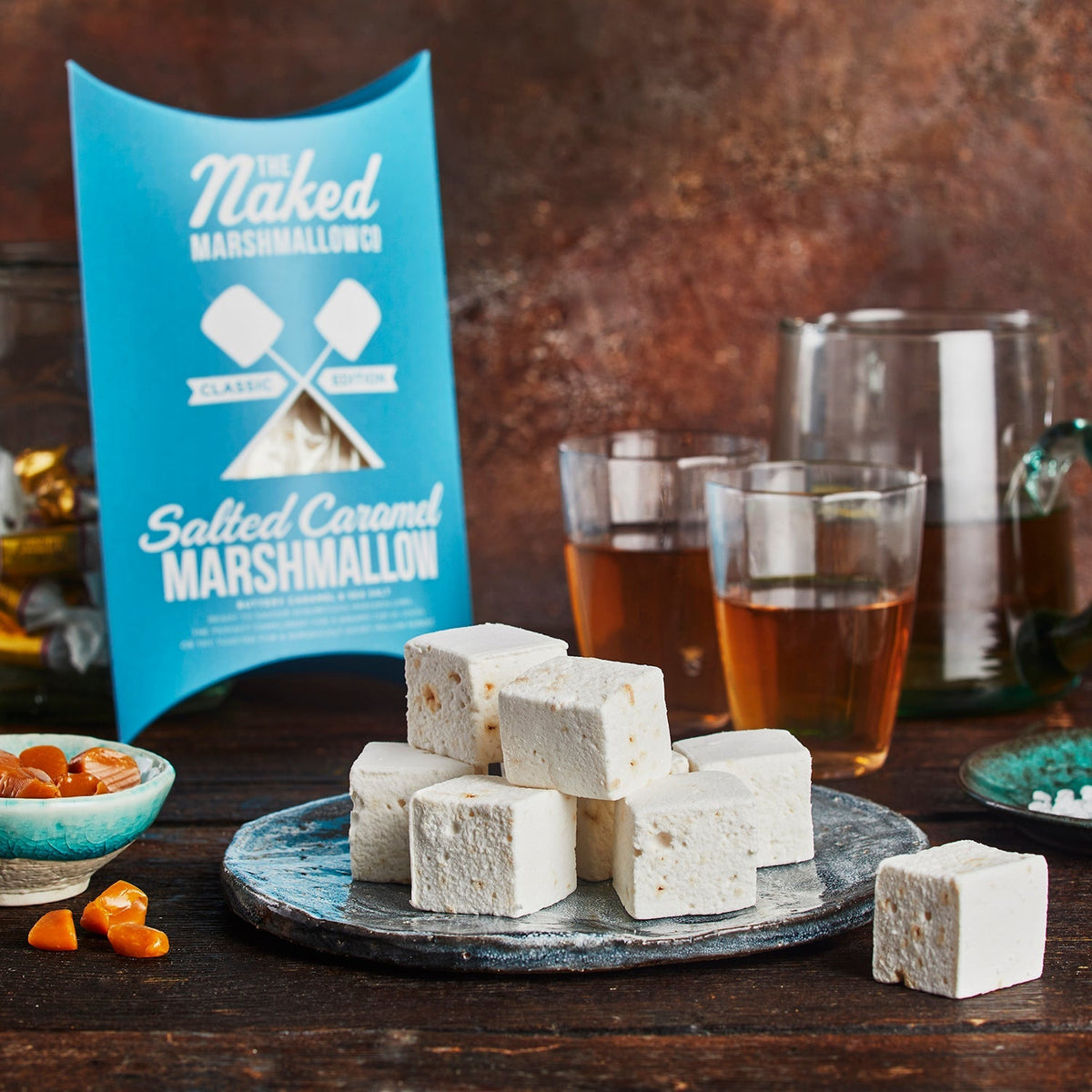 Assorted marshmallows from THE MARSHMALLOW FACTORY Luxury S'mores Gift Set displayed on a wooden surface.