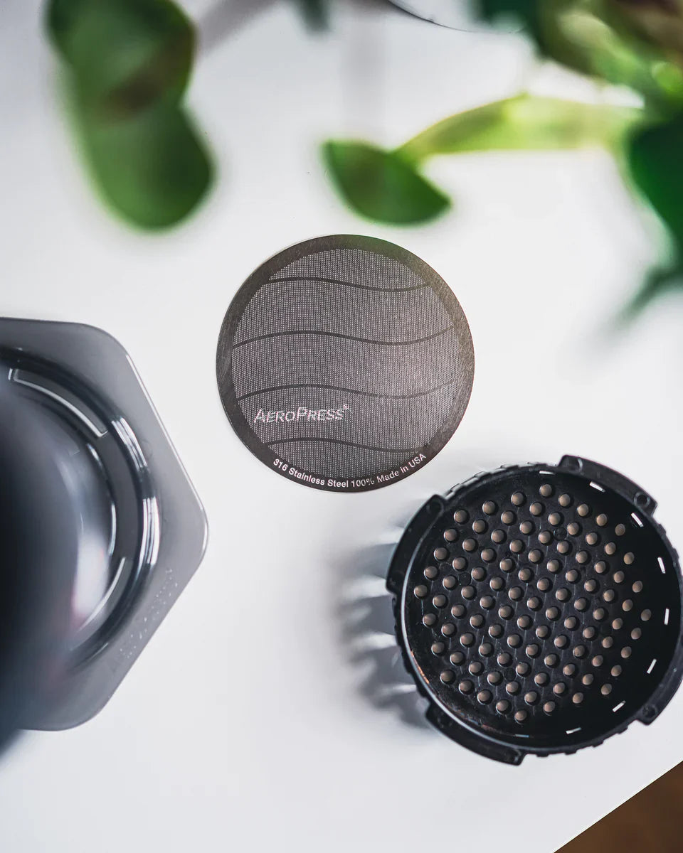 Stainless steel Aeropress filter by Contact Coffee Company Ltd. for coffee brewing, shown in a close-up image.