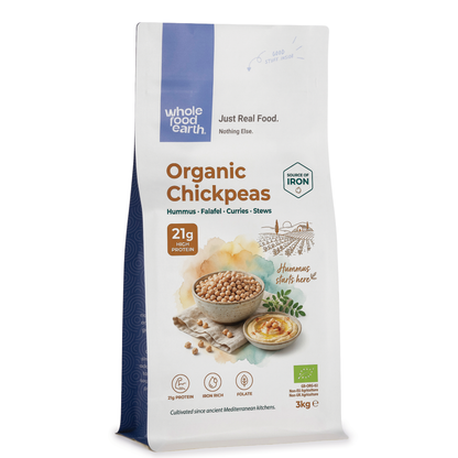Organic chickpeas from Whole Food Earth, displayed in a bowl with some chickpeas scattered around, highlighting fresh, natural legumes.