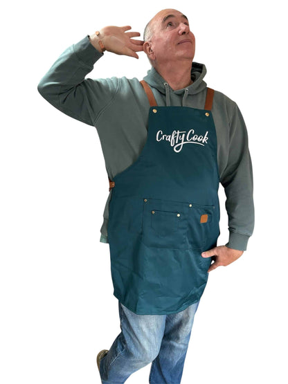 Teal Crafty Cook apron with multiple pockets, made of durable fabric, designed for cooking and baking tasks.
