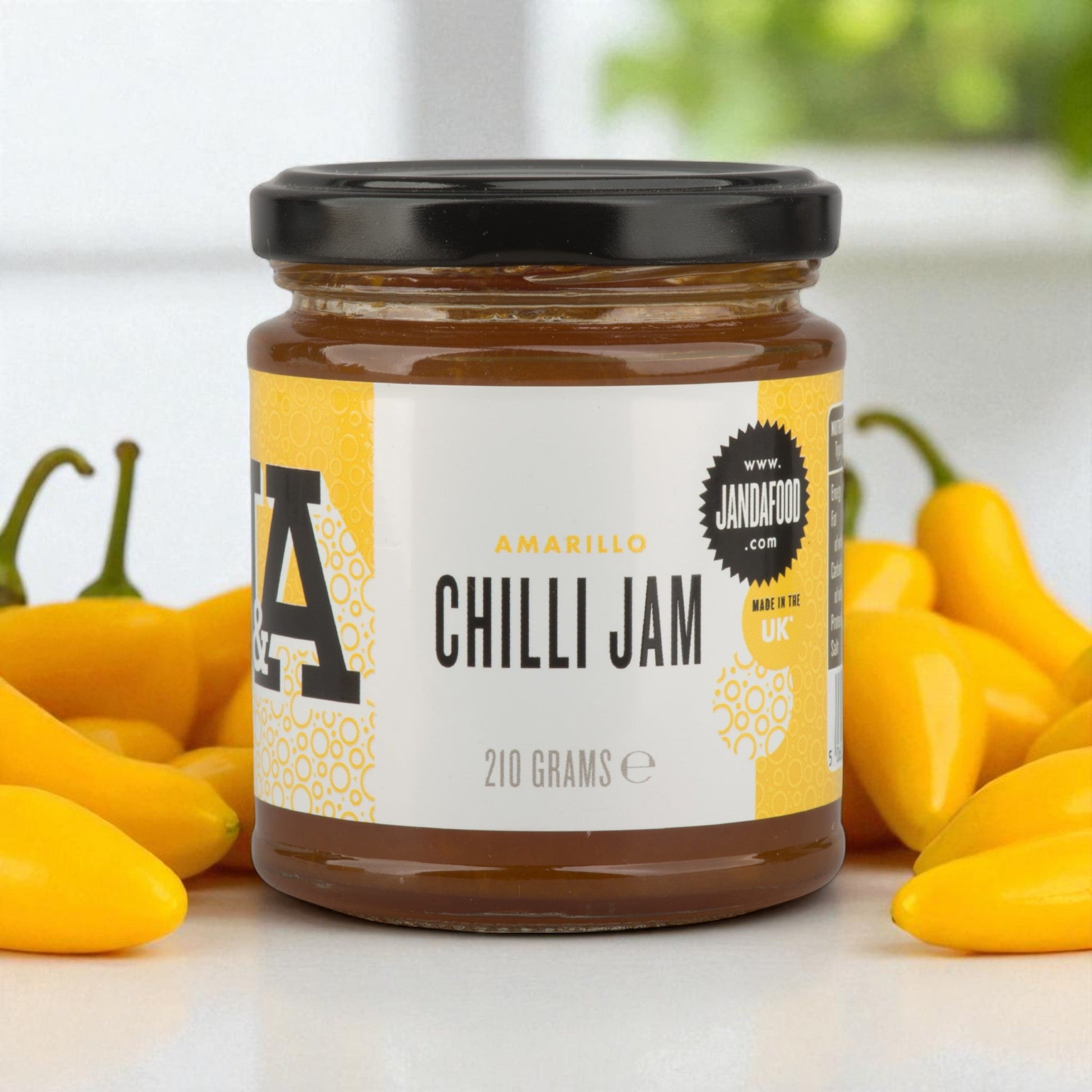 Jar of Amarillo Yellow Chilli Jam by Janda, showcasing bright yellow chili jam with a spoon and cheese, highlighting its sweet and spicy flavor.