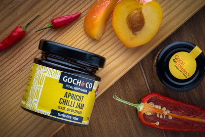 Sweet apricot chilli jam by Goch & Co with vibrant orange apricots and red chilli flakes in a glass jar.