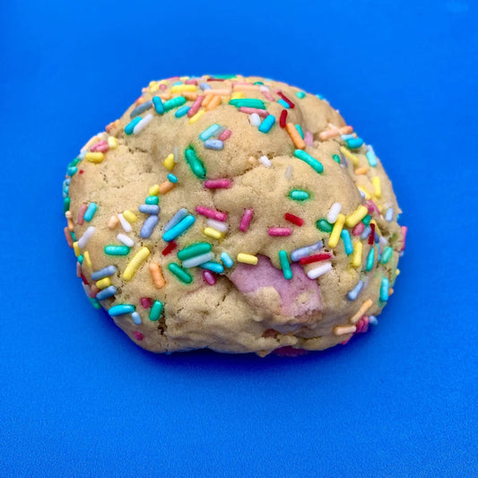 Chocolate birthday cookie from Cool Hog Snacks with colorful sprinkles and festive decorations on top.