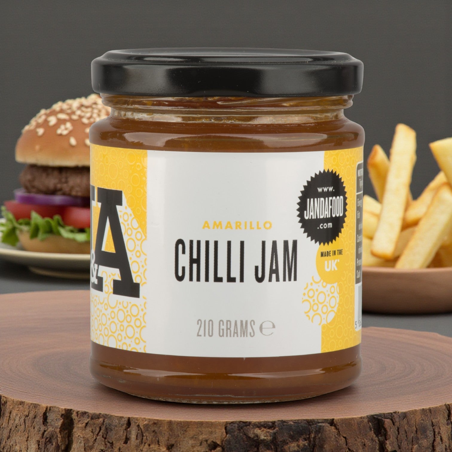 Janda Amarillo Yellow Chilli Jam 210g with cheese and barbecue dishes, featuring a jar of sweet and spicy chilli jam in a burger setting