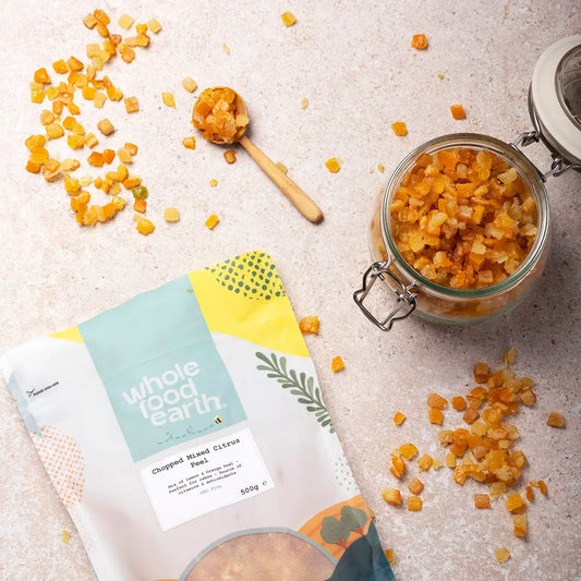 A bowl of chopped mixed citrus peel on a wooden surface, showcasing vibrant orange and yellow citrus pieces for baking and cooking.