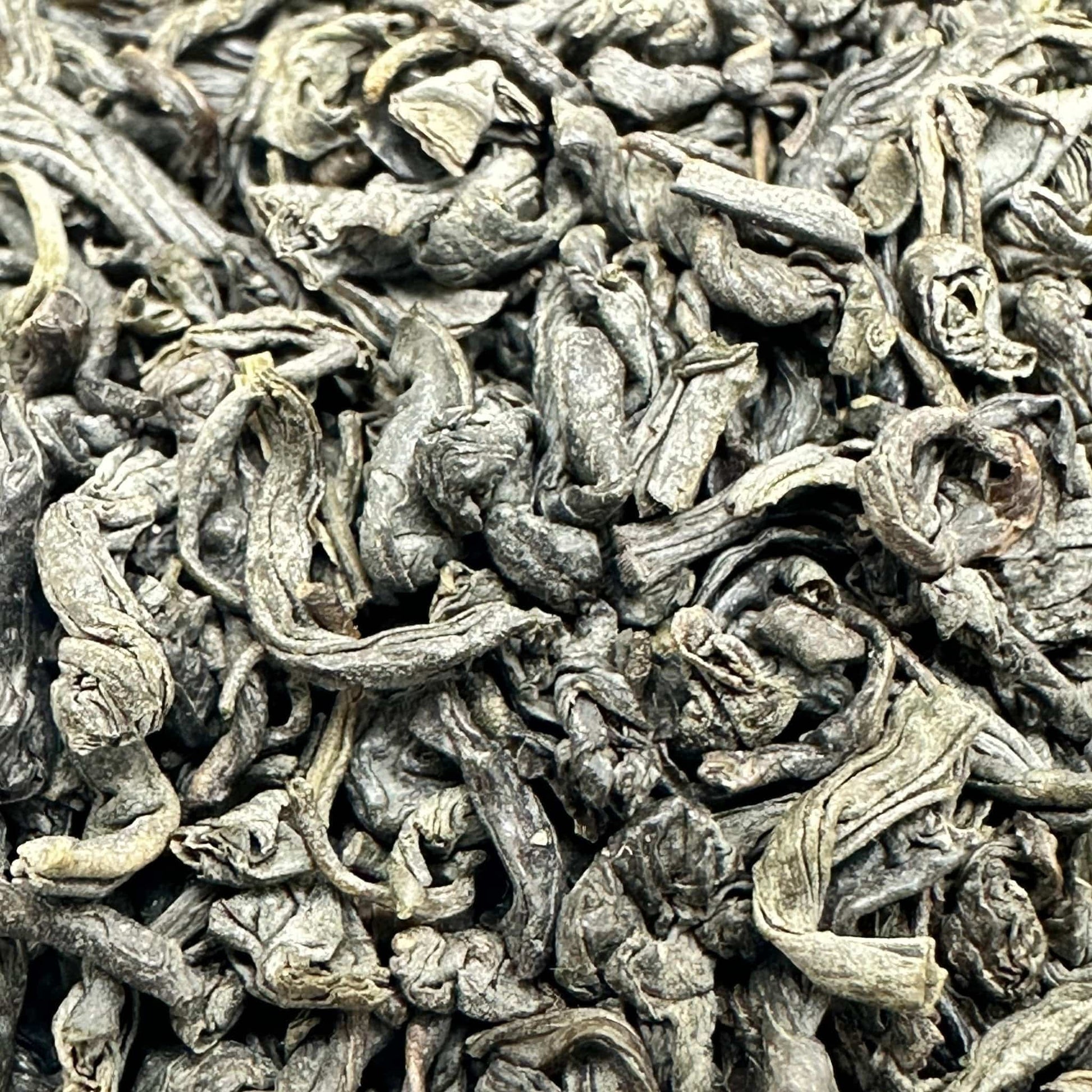 Porter Hill Tea Company Chunmee green tea leaves in a clear jar, showcasing the twisted, light green tea leaves for brewing.