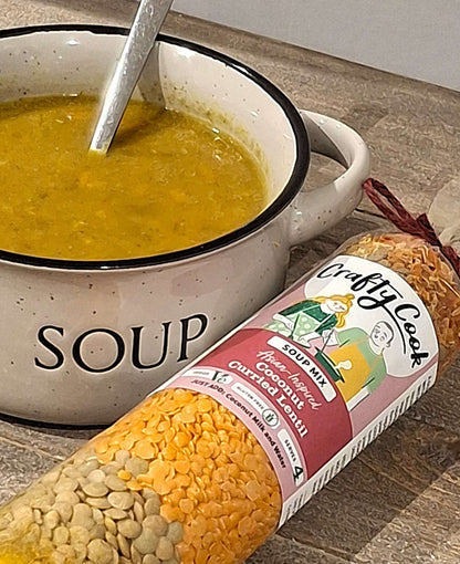 Bowl of coconut curried lentil soup made with Crafty Cook's gluten-free vegan soup mix, served garnished with herbs.