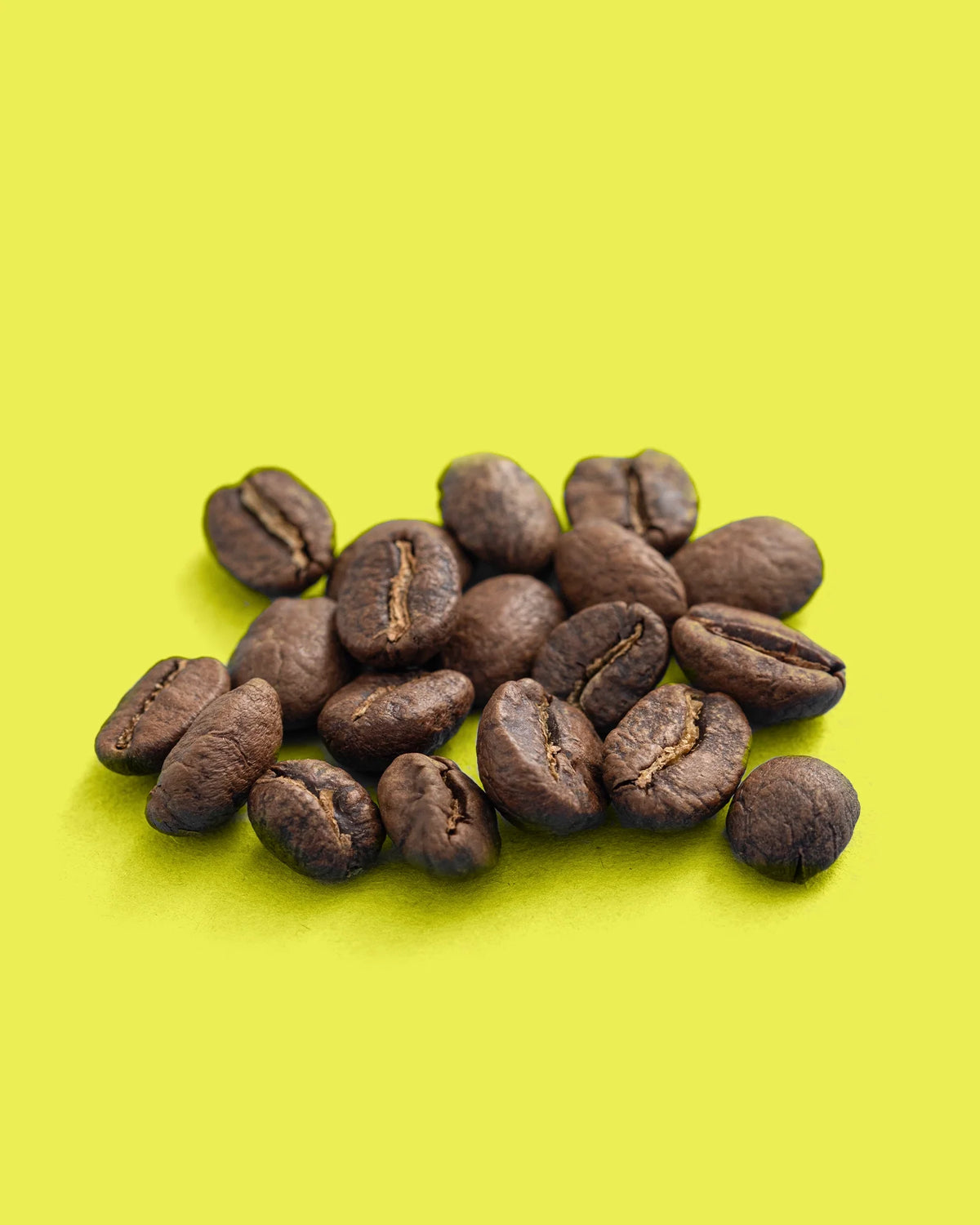 Colombia Dulima Excelso Medium Roast Coffee beans from Recent Beans, showcasing a pile of roasted coffee beans in a natural setting.