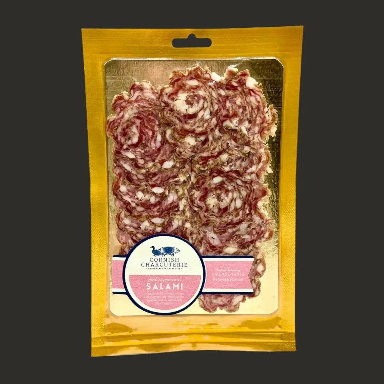 Sliced Cornish pink peppercorn salami from ArtisanBox Selection, showcasing thin slices of flavorful charcuterie on a wooden board.