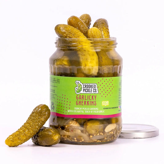Jar of Crooked Pickle Co. Garlicky Gherkins pickles with visible fresh garlic and bright green cucumbers in a clear glass jar.