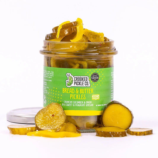 Jar of Crooked Pickle Co. bread and butter pickles with sliced pickles visible inside on a white background.