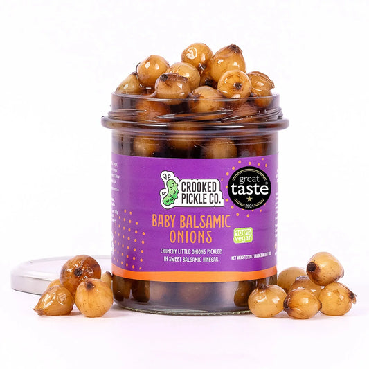 Jar of Crooked Pickle Co Baby Balsamic Onions, pickled onions with a glossy appearance and vibrant color in a clear glass jar.