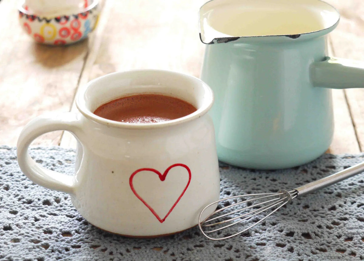 Gorvett & Stone Orange Drinking Chocolate in a cup with orange zest and chocolate pieces on a rustic table.
