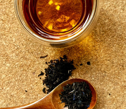 Loose leaf Earl of Colne Valley black tea by Porter Hill Tea Company showing dark, whole tea leaves in a clear glass jar.