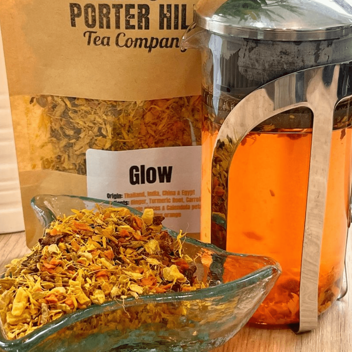 Porter Hill Tea Company's Glow fruit and herbal tea in a clear glass cup with fresh herbs and fruit slices for a vibrant, refreshing look.
