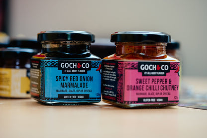 Spicy red onion marmalade by Goch & Co, showing a jar with vibrant red onion slices and a glossy, flavorful spread inside.