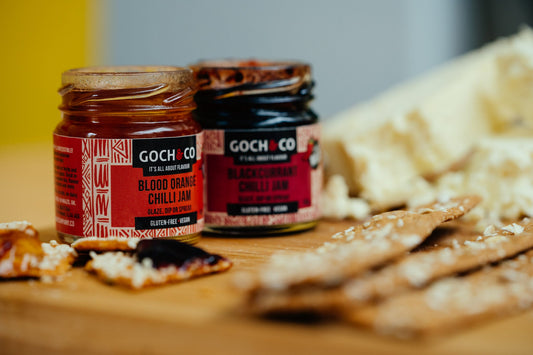 Goch & Co condiment and sauce subscription box with various bottles and jars of flavorful sauces on a white background.