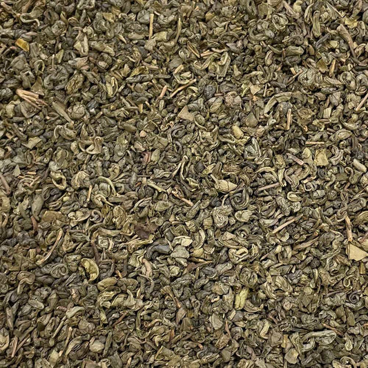 Loose leaf Gunpowder tea from High Teas, Temple of Heaven blend, showing tightly rolled green tea leaves in a natural setting.
