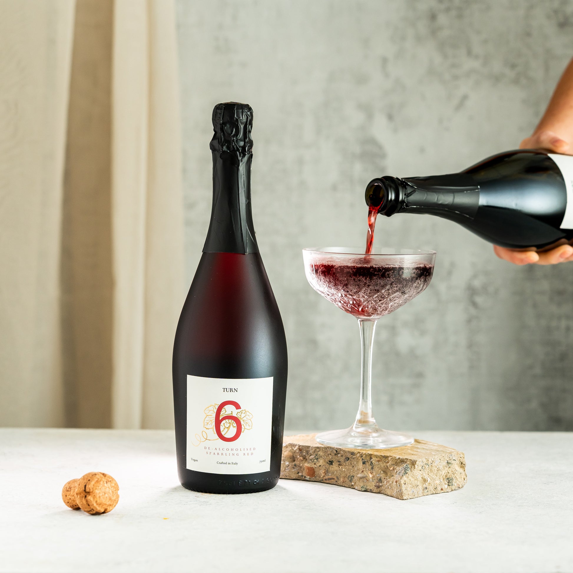 Glass of alcohol-free sparkling red wine from Turn 6 Premium Alcohol-Free Wine, showcasing vibrant red color and bubbles.