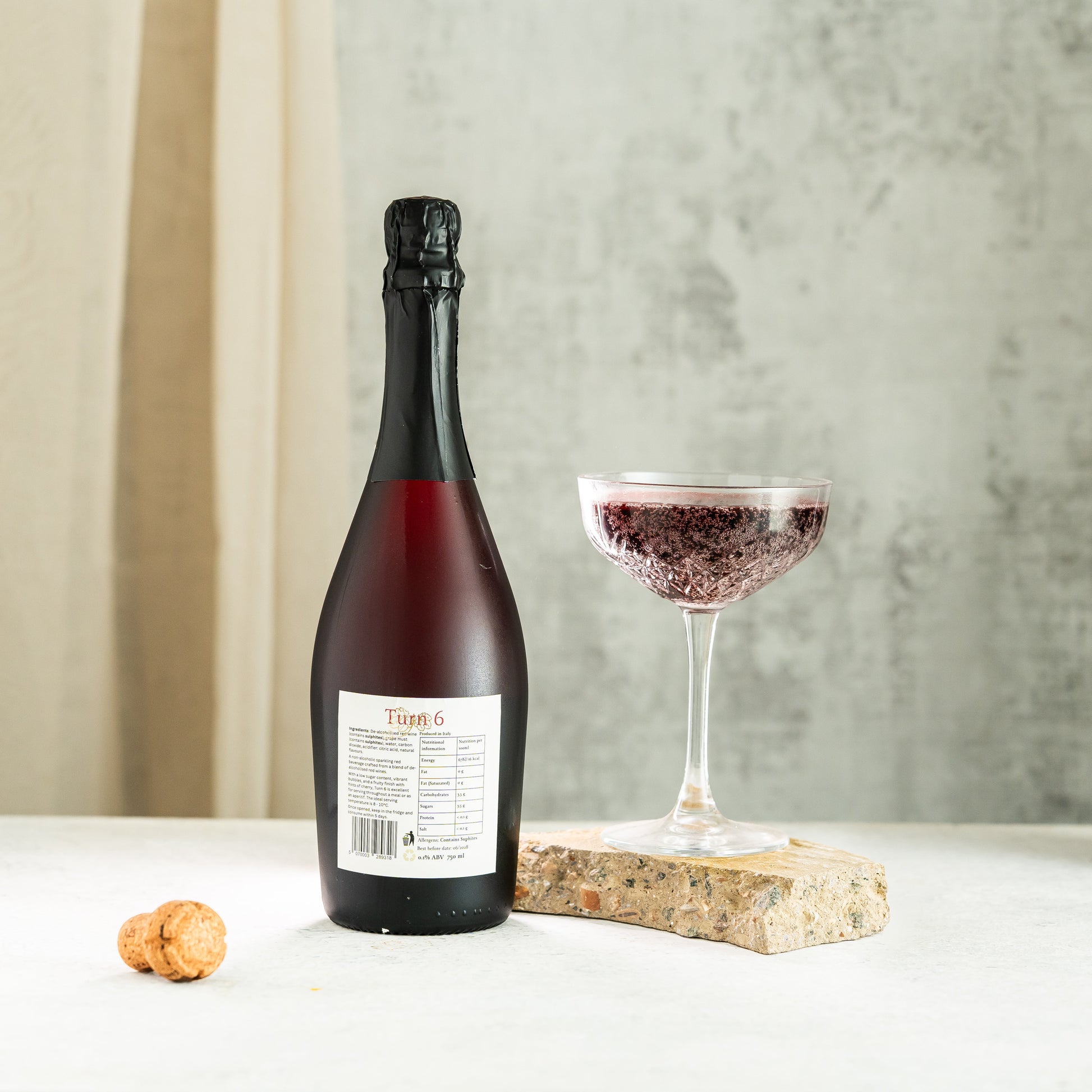 High-resolution image of Turn 6 Premium Alcohol-Free Sparkling Red Wine in a glass, showcasing its vibrant red color and effervescent bubbles.