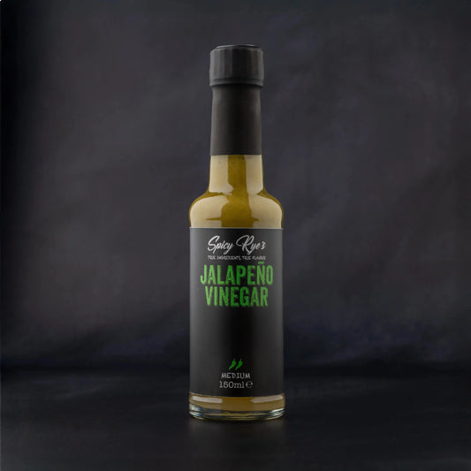 Spicy Ryes Jalapeño Vinegar bottle with vibrant green jalapeño peppers and clear liquid, on a rustic wooden surface.