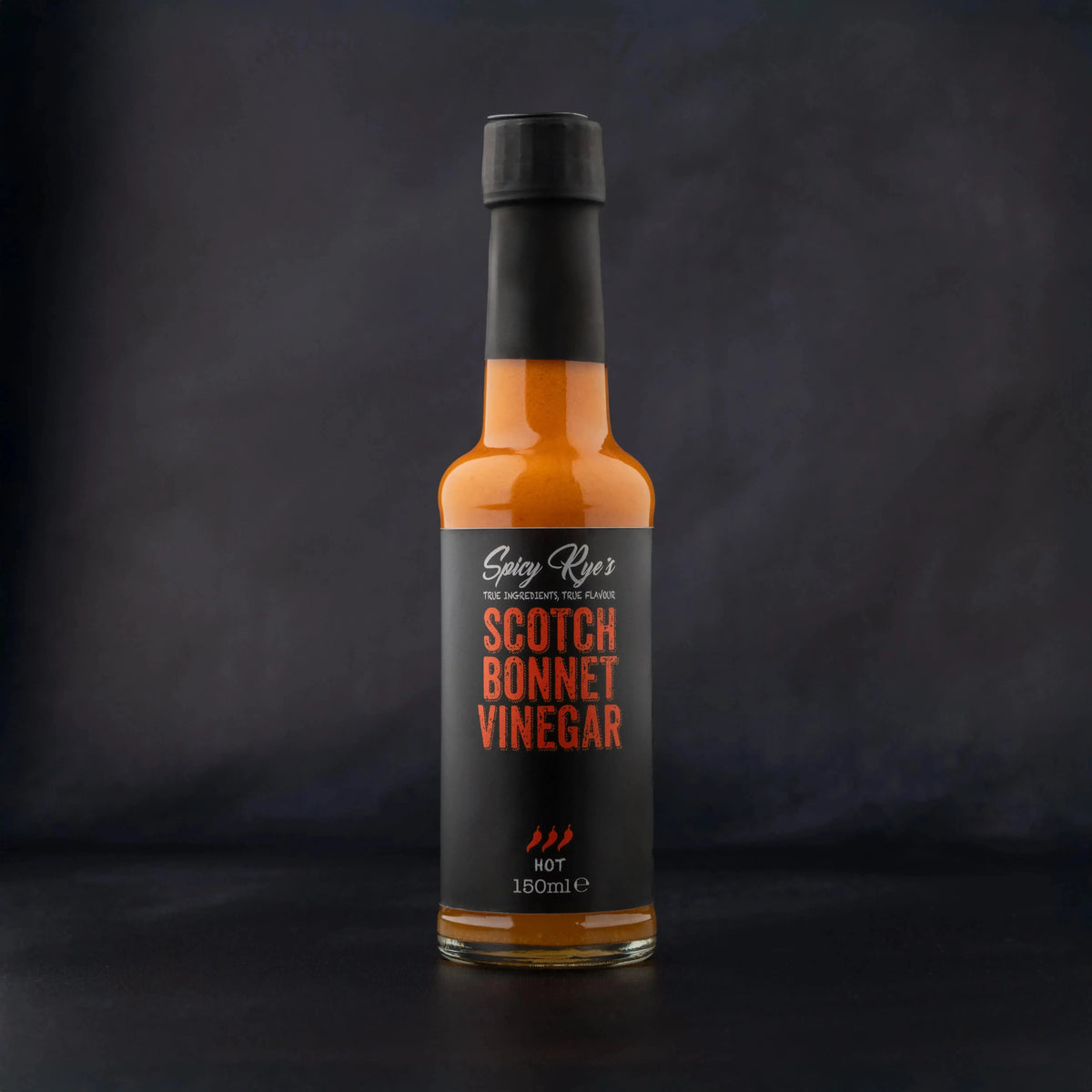 Spicy Ryes Scotch Bonnet Vinegar bottle with label, showcasing bright yellow and red design on a clear glass container.