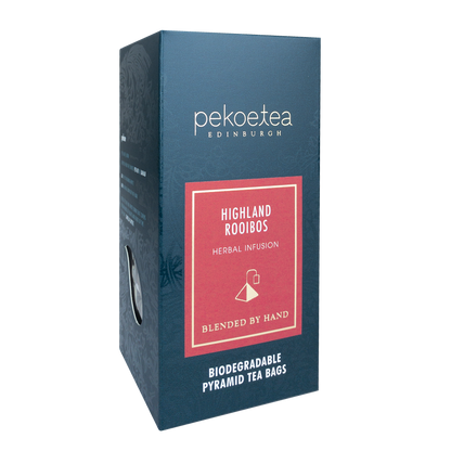 Cups of PekoeTea Edinburgh Highland Rooibos herbal tea with dried rooibos leaves in a rustic setting.