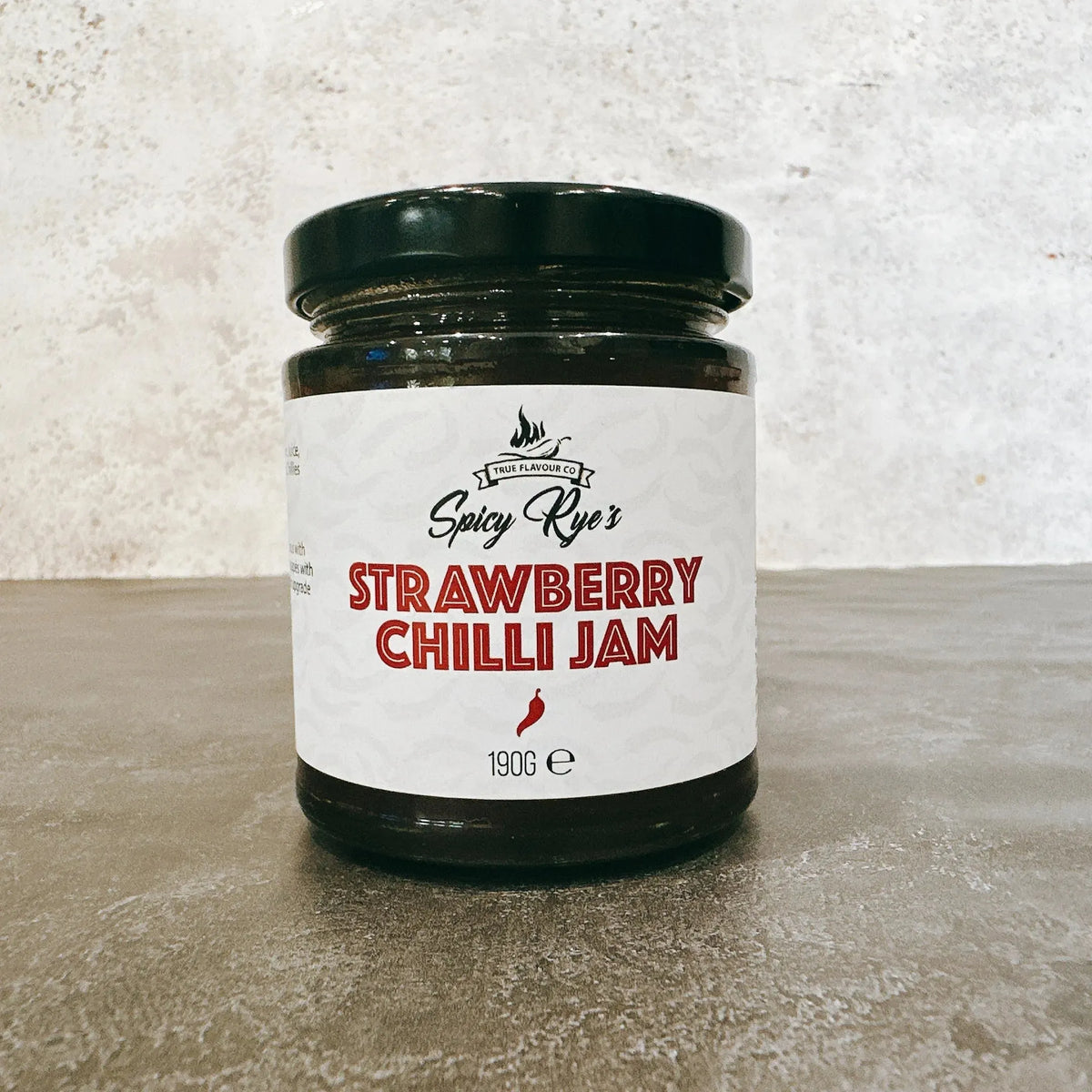 Spicy Ryes Strawberry Chilli Jam jar with vibrant label, showcasing the bright red jam with chili flakes inside.