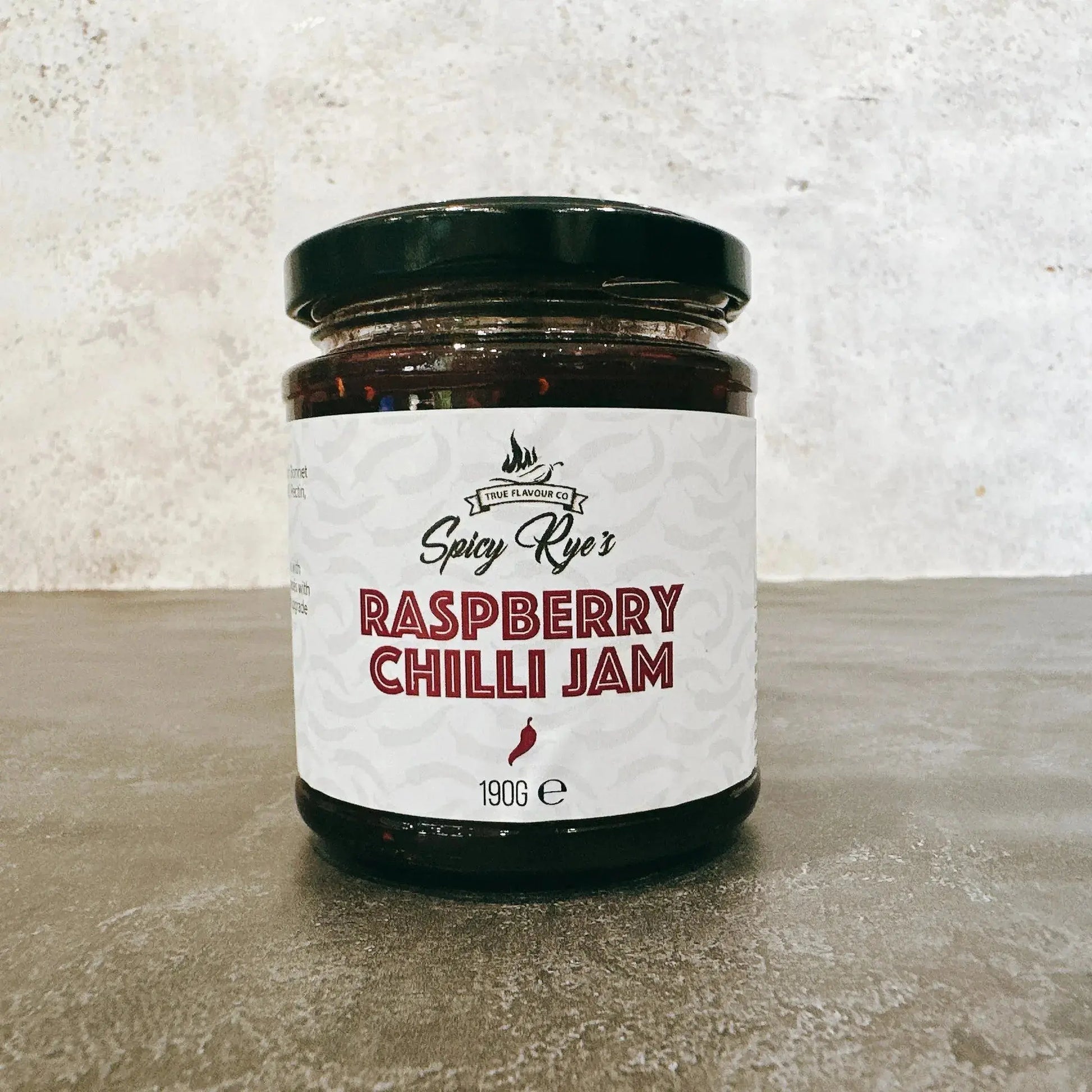 Spicy Ryes Raspberry Chilli Jam jar with vibrant red jam and chili peppers on the label, showcasing the flavorful condiment.