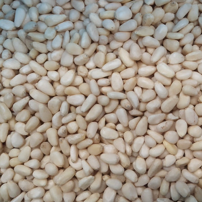 Whole Food Earth pine nuts, raw nuts and seeds in a clear bowl, close-up view of light beige pine nuts on a white background.