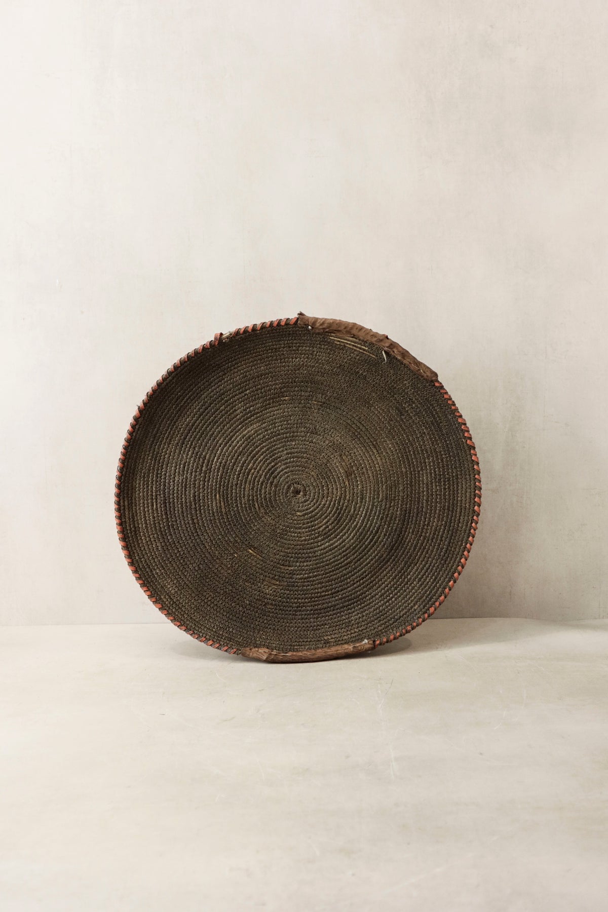 Handwoven wall basket from Chad by Botanical Boys, made of natural fibers, displayed hanging on a wall.