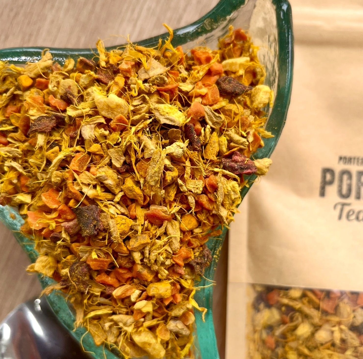 Porter Hill Tea Company Glow fruit and herbal tea in a clear glass mug with vibrant herbal ingredients visible.