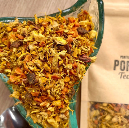 Porter Hill Tea Company Glow fruit and herbal tea in a clear glass mug with vibrant herbal ingredients visible.