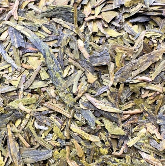 Fresh organic Dragonwell green tea leaves from Porter Hill Tea Company, displayed in a clear glass jar.