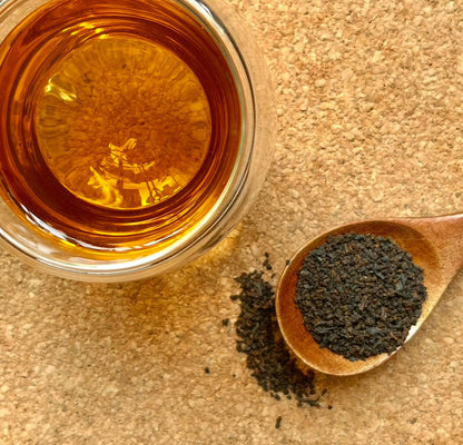 A box of Porter Hill Tea Company Irish Breakfast black tea with loose tea leaves and a steaming cup of brewed tea.