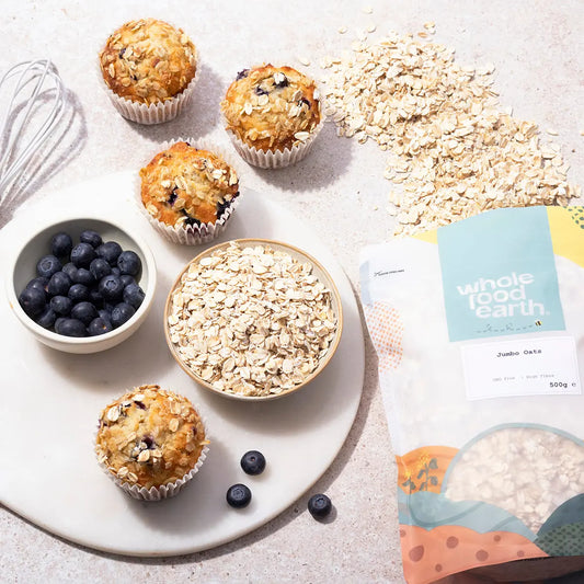 Bowl of ArtisanBox Jumbo Oats with fresh fruit and nuts on a rustic wooden table, showcasing healthy breakfast ingredients.