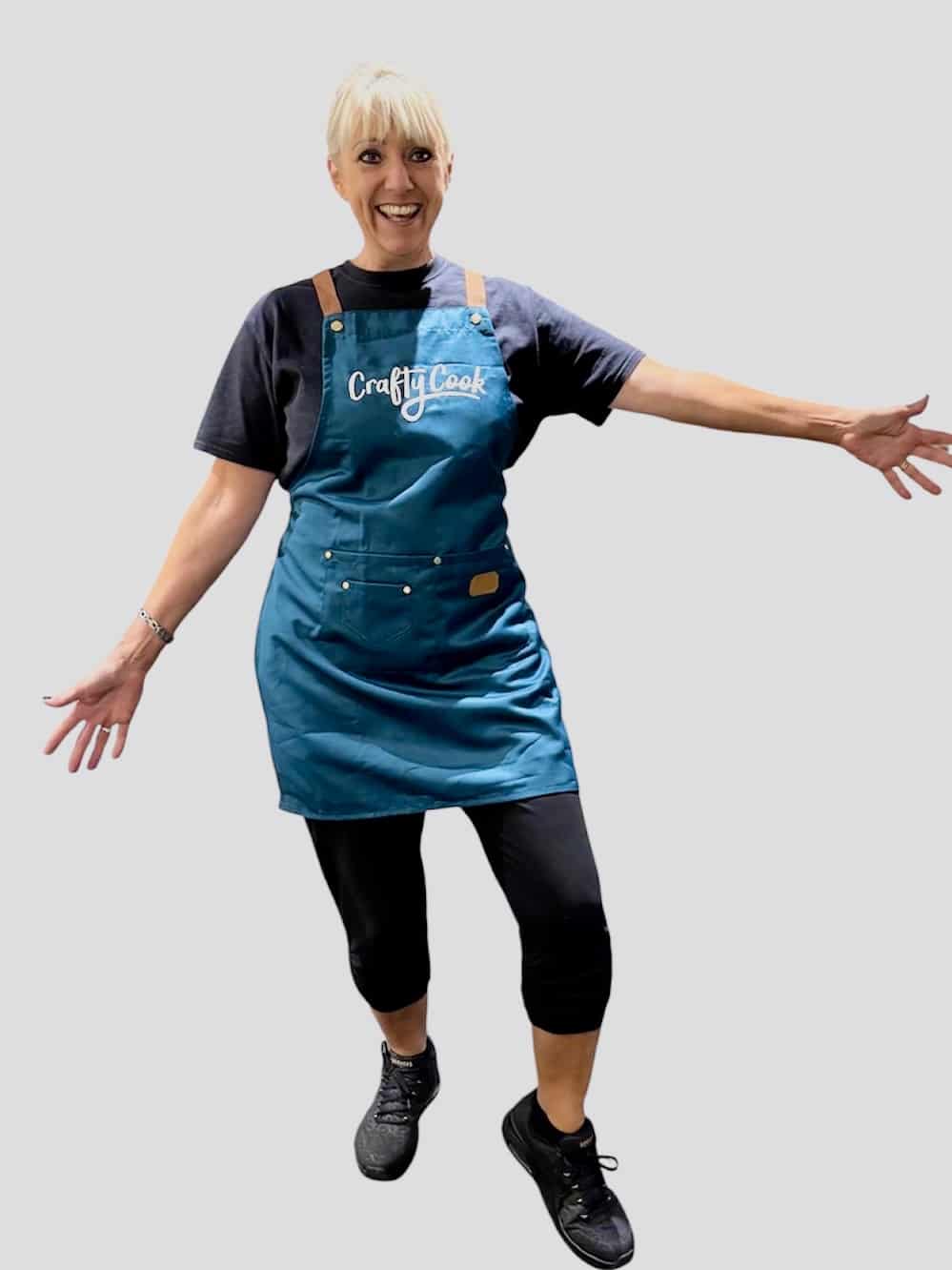 Teal Crafty Cook apron with multiple pockets, made for cooking and baking, featuring adjustable straps and durable fabric.