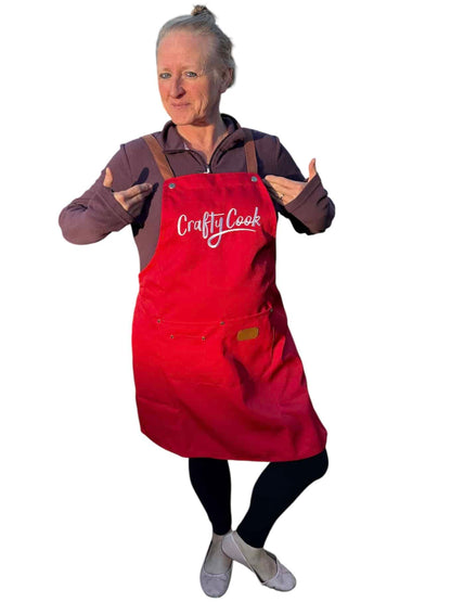 Red Crafty Cook apron with pockets, featuring adjustable straps and multiple storage compartments for cooking and baking.
