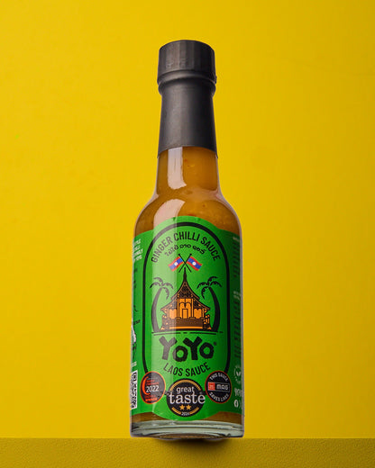 Bottle of YoYo Laos Signature Ginger Chilli Sauce with fresh ginger and red chillies, showcasing the spicy, flavorful sauce.