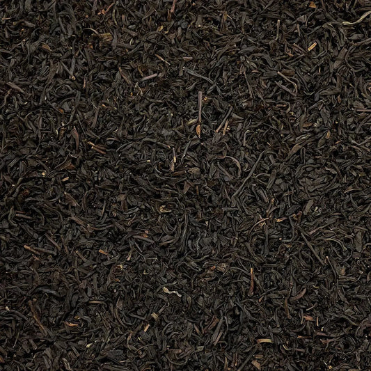 Loose leaf Lapsang Souchong Butterfly tea from High Teas, showing dark, twisted tea leaves in a clear glass jar.