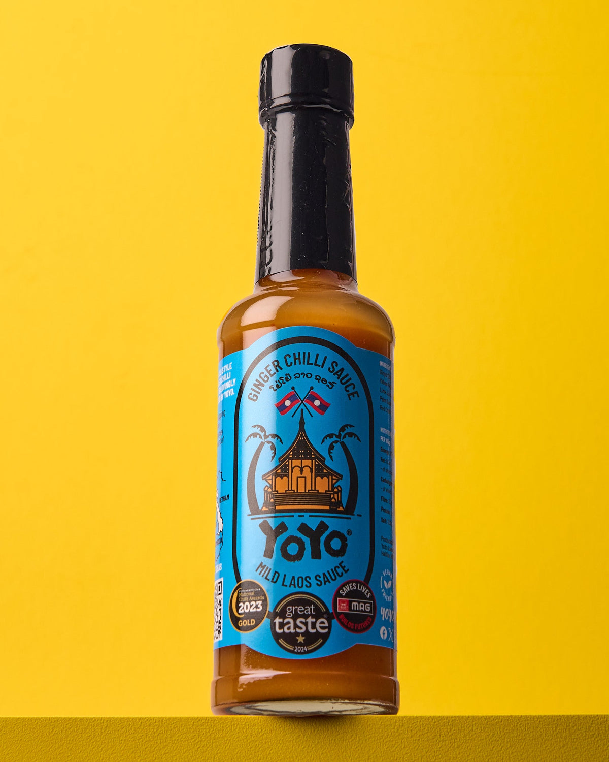Bottle of YoYo Laos Sauce "MILD" Ginger Chilli Sauce showing the label and sauce inside the transparent bottle.