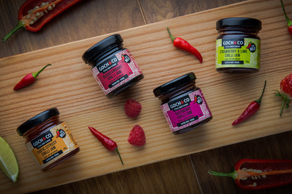 Assortment of Goch & Co Sweet-Savoury Chilli gift set with multiple jars of spicy and flavorful food items arranged together.