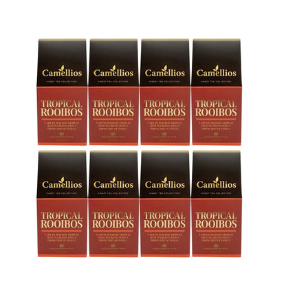 A cup of brewed Camellios Tropical Rooibos tea with vibrant tea infusions and fresh tropical fruits on a wooden table.