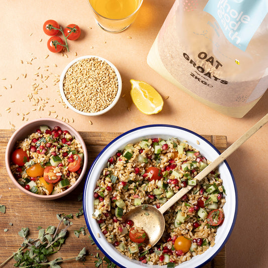 Bowl of raw oat groats from ArtisanBox with a spoon, placed on a rustic wooden table, showcasing healthy whole grain oats.