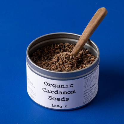 Organic cardamom seeds from Whole Food Earth, displayed in a clear glass jar on a wooden surface, highlighting fresh, whole herbs.