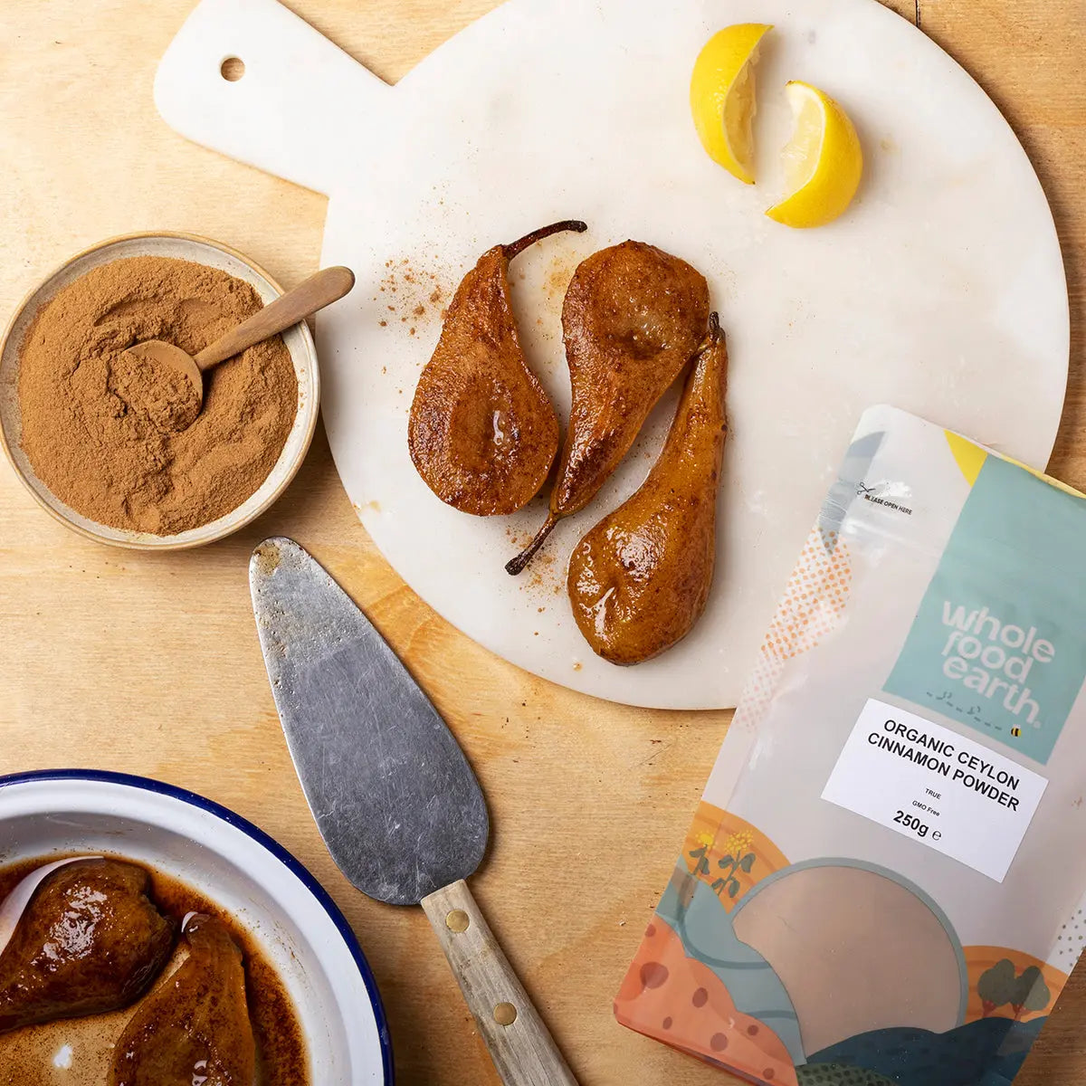Organic Ceylon cinnamon powder from Whole Food Earth displayed in a jar with cinnamon sticks and a spice grinder on a wooden surface.