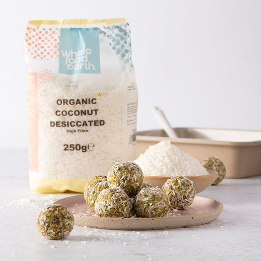 Organic coconut desiccated in a bowl, dried fruit product from Whole Food Earth, with shredded coconut pieces on a wooden surface.