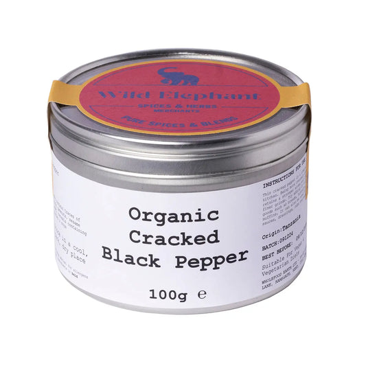 Organic cracked black pepper from Wild Elephant, displayed in a clear container showing coarse black peppercorns.